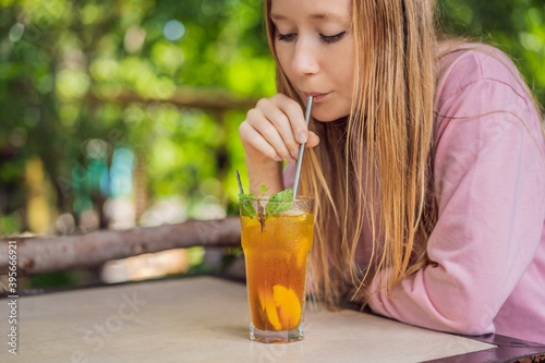 Eco friendly woman using reusable stainless steel straw to drink fruit tea photo