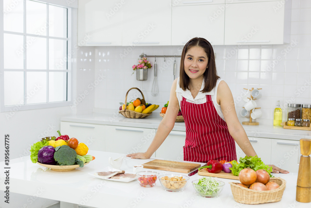 Young Asian woman wearing an apron in the kitchen preparing to cook. Young Asian woman wearing an apron in the kitchen preparing to cook.