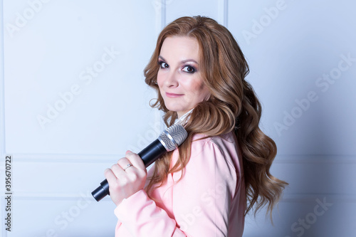 elegant woman in pink suit with microphone in hands