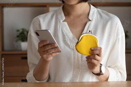 がま口財布を持ってスマホを確認する女性
