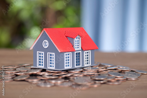Small house model placed on a pile of dollar coins
