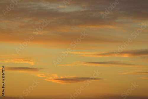 Sun below the horizon and clouds in the fiery dramatic orange sky at sunset or dawn backlit by the sun. Place for text and design