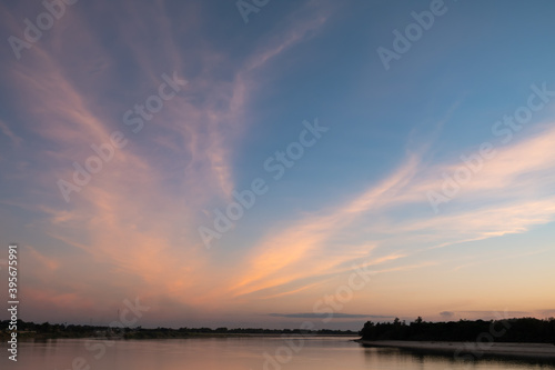 Sunset sky and Cirrus fibratus clouds over the riverbank of Mekong river. Blue and orange colors evening sky background. photo