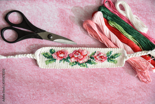 Slika na platnu Woven DIY friendship bracelet with bright flower pattern Rose near scissors and