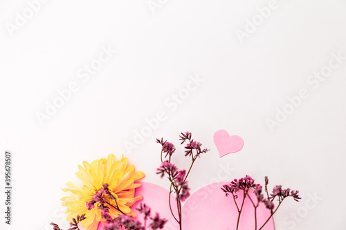 A large pink hear decorated with small pink flowers and yellow chrysanthemums on a white background