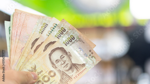 Man hand holding banknotes, Thai money, blurred background, business idea, shopping