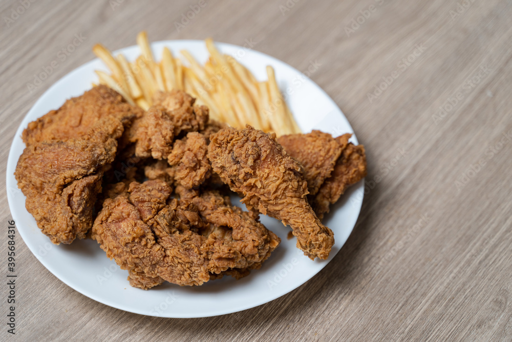 Crispy fried chicken with french fries in white plate on a wooden table. Crispy fried chicken with french fries in white plate on a wooden table.