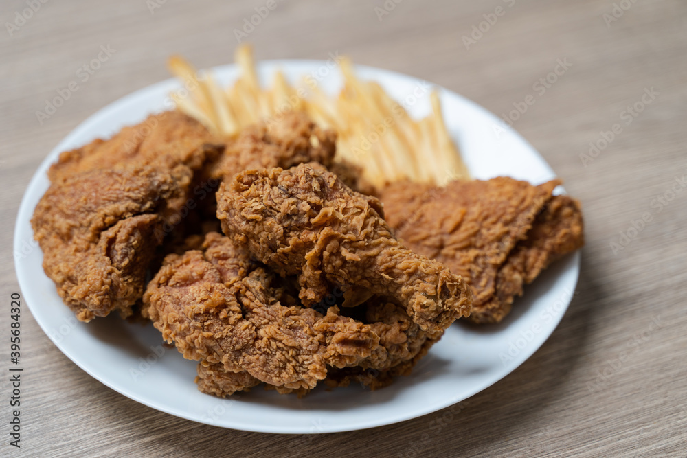 Crispy fried chicken with french fries in white plate on a wooden table. Crispy fried chicken with french fries in white plate on a wooden table.