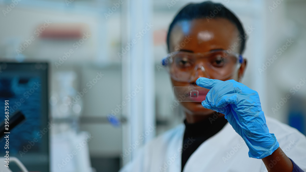 Close up of black chemistry doctor looking at virus test in equipped lab. African scientist working with various bacteria, tissue and blood samples, concept of pharmaceutical research for antibiotics Close up of black chemistry doctor looking at virus test in equipped lab. African scientist working with various bacteria, tissue and blood samples, concept of pharmaceutical research for antibiotics