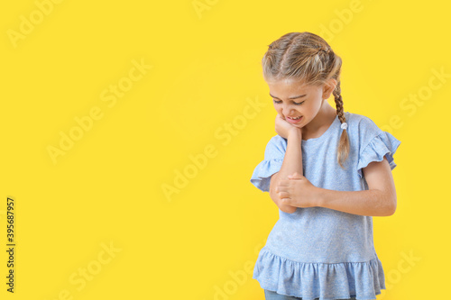 Allergic little girl scratching herself on color background
