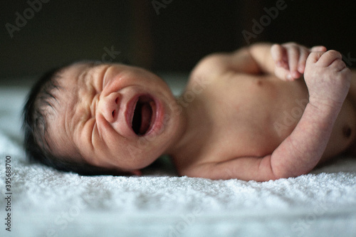 Newborn baby boy crying on the bed