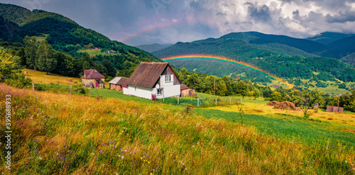 Huge ainbow at the summer rain. Panoramic morning view of Kvasy village, Transcarpathian, Ukraine. Amazing landscape of Carpathian mountains. Beauty of countryside concept background.
