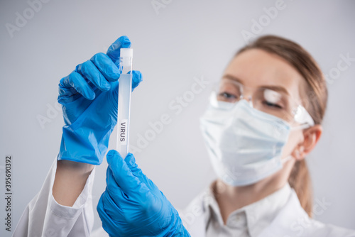 Macro shot of microbiologist in protective clothing study biological tube with vaccine on white background. Research and development concept. News feed.