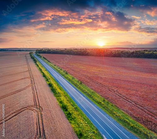 Fantastic sunrise on Ukrainian countrysidewith asphalt road among the field of wheat. Aerial morning view of countryside, Ternopil region, West Ukraine, Europe. Landscape photography.. photo