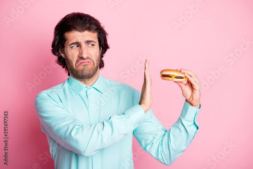 Fényképezés Photo portrait of man refusing to eat disgusting cheeseburger isolated on pastel