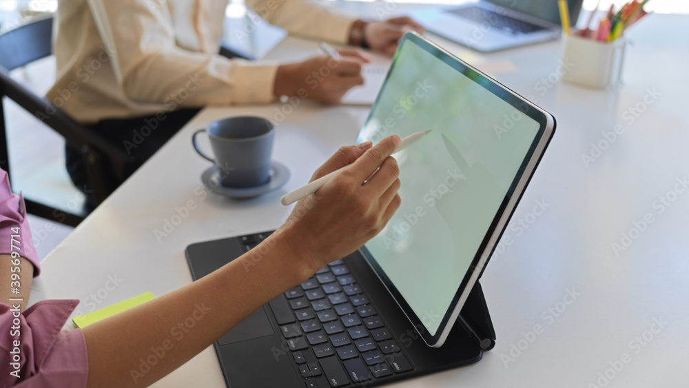 Female hands with stylus pen working on mock up digital tablet in meeting room