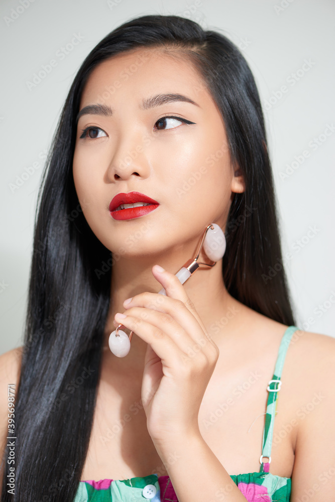 Face massage. Smiling woman using rose quartz facial roller for skin care, beauty treatment on white isolate background.