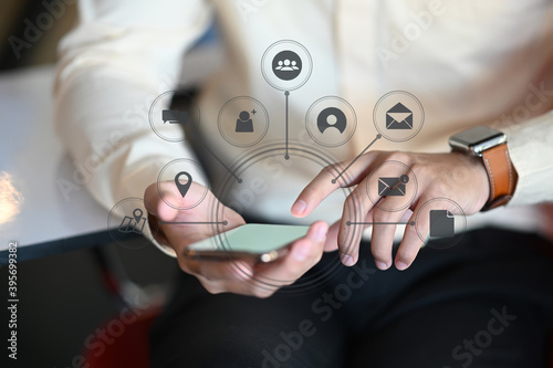 Cropped shot of businessman hands using smartphone with media icons and symbol collection.