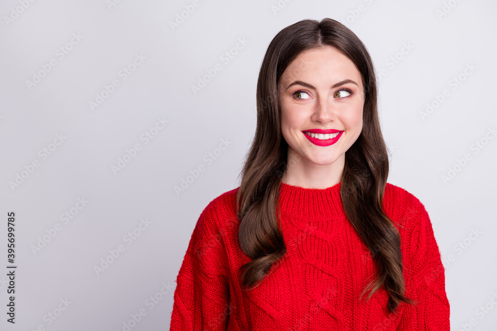 Photo portrait of curious brunette wearing red sweater looking at blank space smiling isolated on pastel grey color background