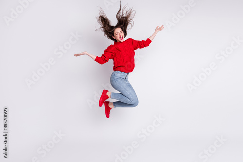 Full length body size photo of jumping girl throwing hair laughing in red jumper jeans isolated on grey pastel color background