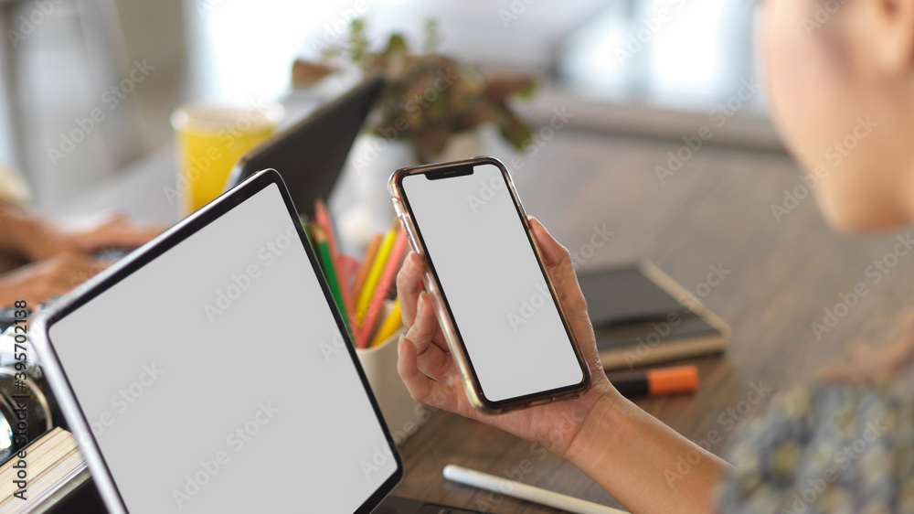 Close up view of female using smartphone and tablet on wooden table Close up view of female using smartphone and tablet on wooden table