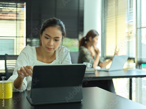 Female office worker working with digital tablet on worktable in office room