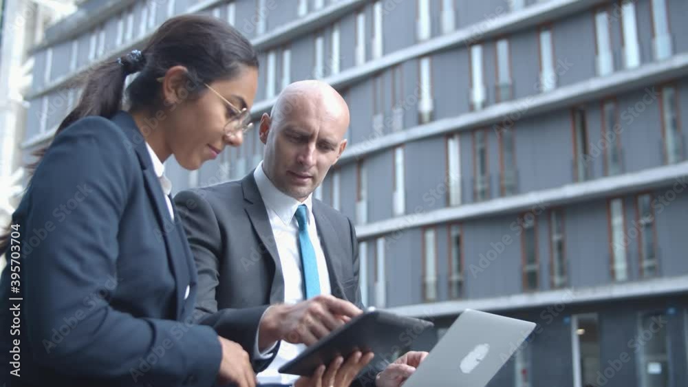 Startup manager presenting project to investor. Business colleagues watching and discussing content on tablet outside. Side view. Business meeting and communication concept