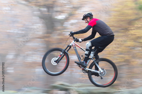 Man cycling fast with mountainbike in a forest in fall