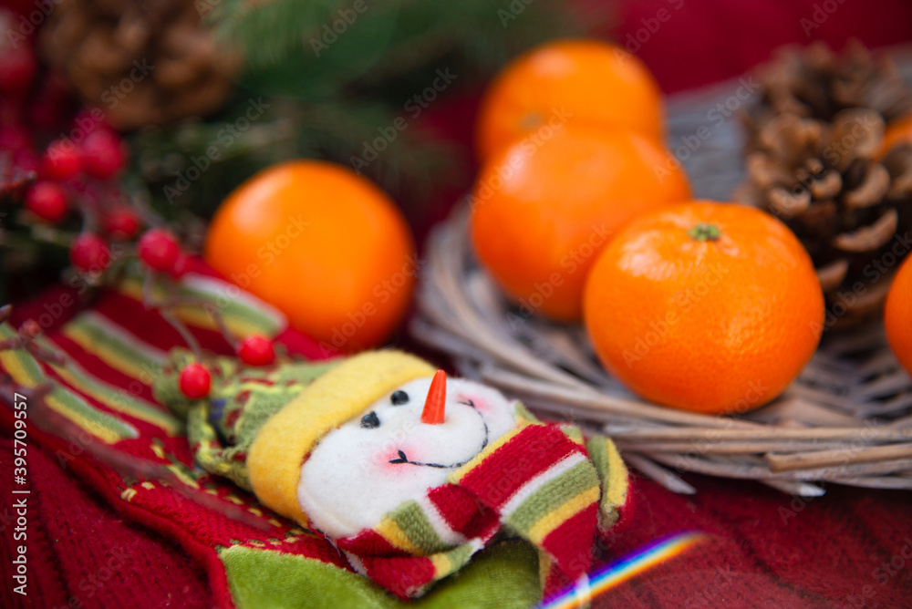 Christmas decoration snowman on red knitwear next to tangerines. Christmas colorful background from a set of Christmas decorations