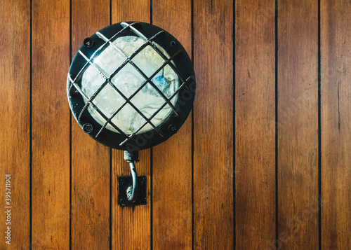 Vintage electric lamp on wooden wall, old sailboat lighting equipment.