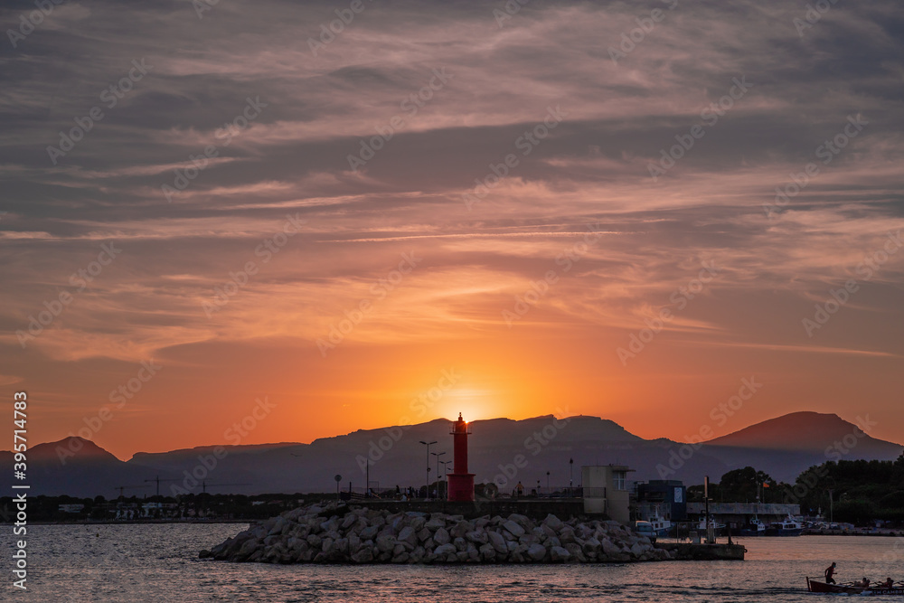 puesta de sol sobre el faro del puerto de cambrils, tarragona