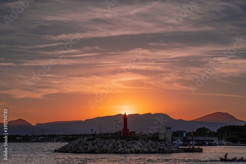 puesta de sol sobre el faro del puerto de cambrils, tarragona