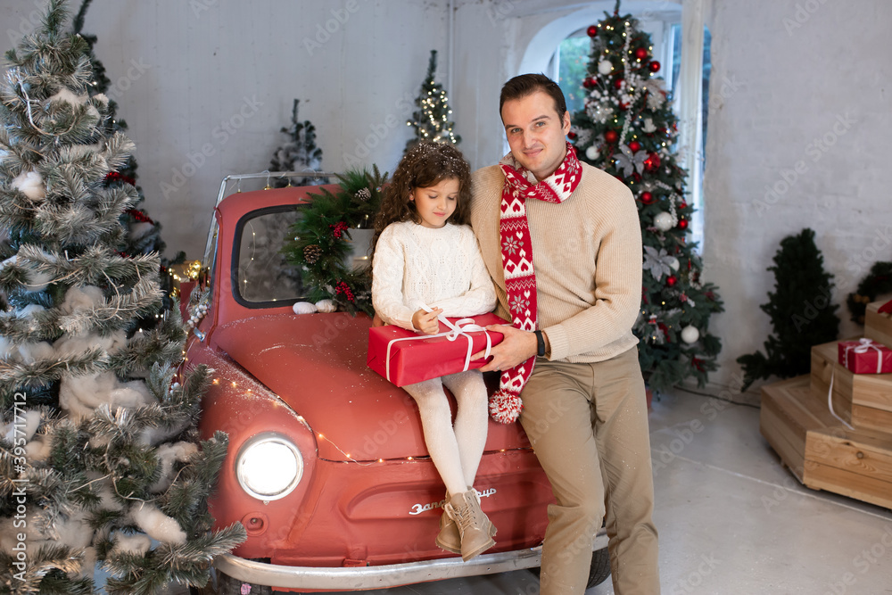 Father with his cute daughter near Christmas tree and car