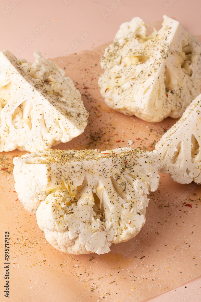 Fototapeta premium cauliflower with spices and herbs on baking paper close up.