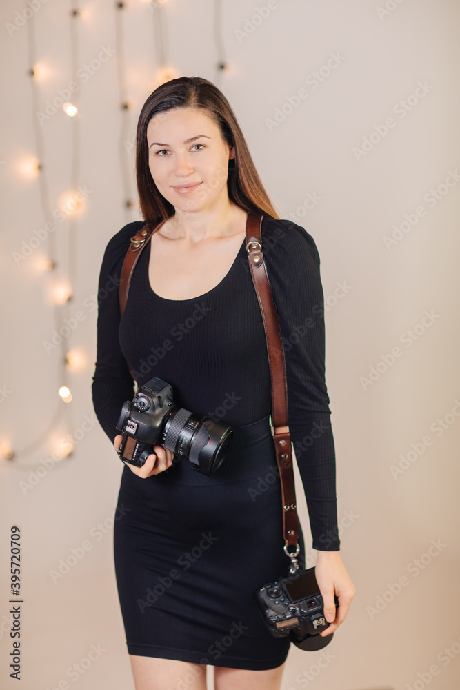 young brunette woman dressed in black with 2 cameras on a leather strap young brunette woman dressed in black with 2 cameras on a leather strap