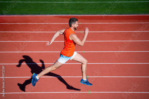 athletic muscular male running on racetrack at outdoor stadium, aim © be free
