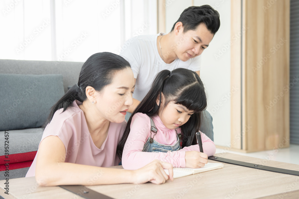 Education concept.Portrait enjoy happy smiling love asian family father and mother with little asian girl learning and writing in book with pen making homework at home. Education concept.Portrait enjoy happy smiling love asian family father and mother with little asian girl learning and writing in book with pen making homework at home.