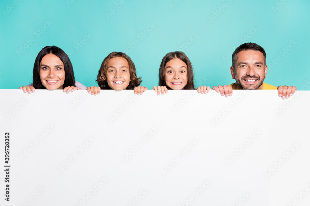 Photo portrait of big family with little kids peaking over white banner isolated on vivid teal colored background Photo portrait of big family with little kids peaking over white banner isolated on vivid teal colored background