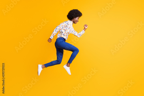 Full size profile side photo of brunette lady wear blue pants white print shirt jump run sale isolated on yellow color background