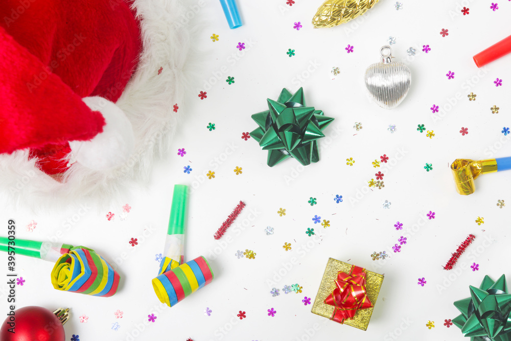 Christmas and New Year decorations with confetti, gift boxes, Santa Claus hat and party blowouts. Colorful party flat lay.