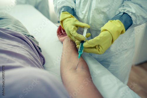 Doctor with bacteriological protective suits injecting a vaccine to a patient