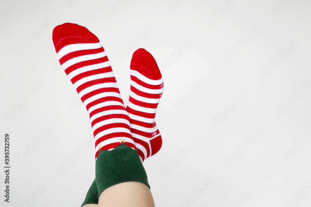 Female feet in Christmas socks on white background. Concept of New Year celebration, elf costume Female feet in Christmas socks on white background. Concept of New Year celebration, elf costume