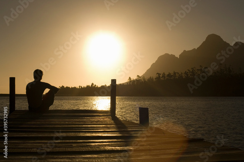 Man Sitting On Dock By Lake © moodboard