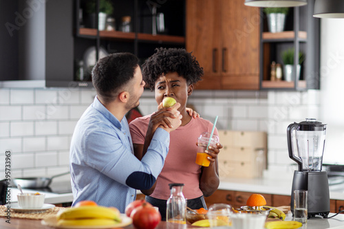 Multiethnic couple in the kitchen with smoothie and fruits on healthy morning breakfast