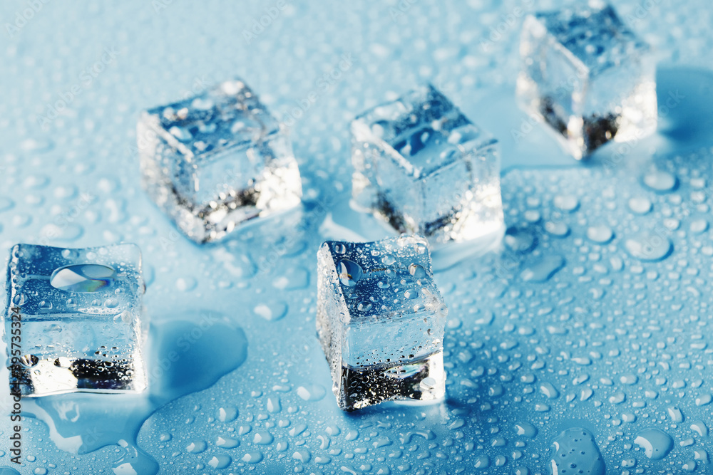 Close-up ice cubes with melt water drops scattered on a blue background. Close-up ice cubes with melt water drops scattered on a blue background.