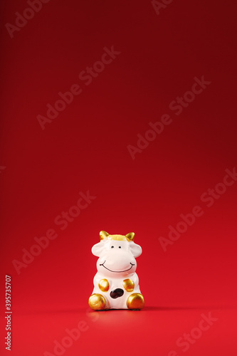 Figurine of a cow from on a red background, free space for text. © Alexander