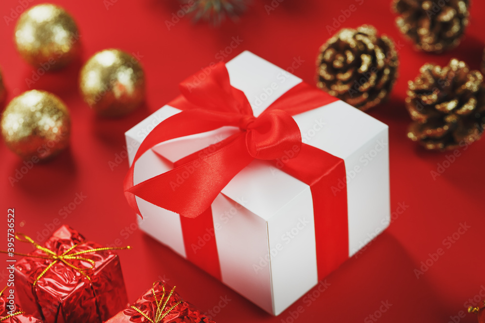 Box with a red bow around Christmas decorations on a red background. Box with a red bow around Christmas decorations on a red background.