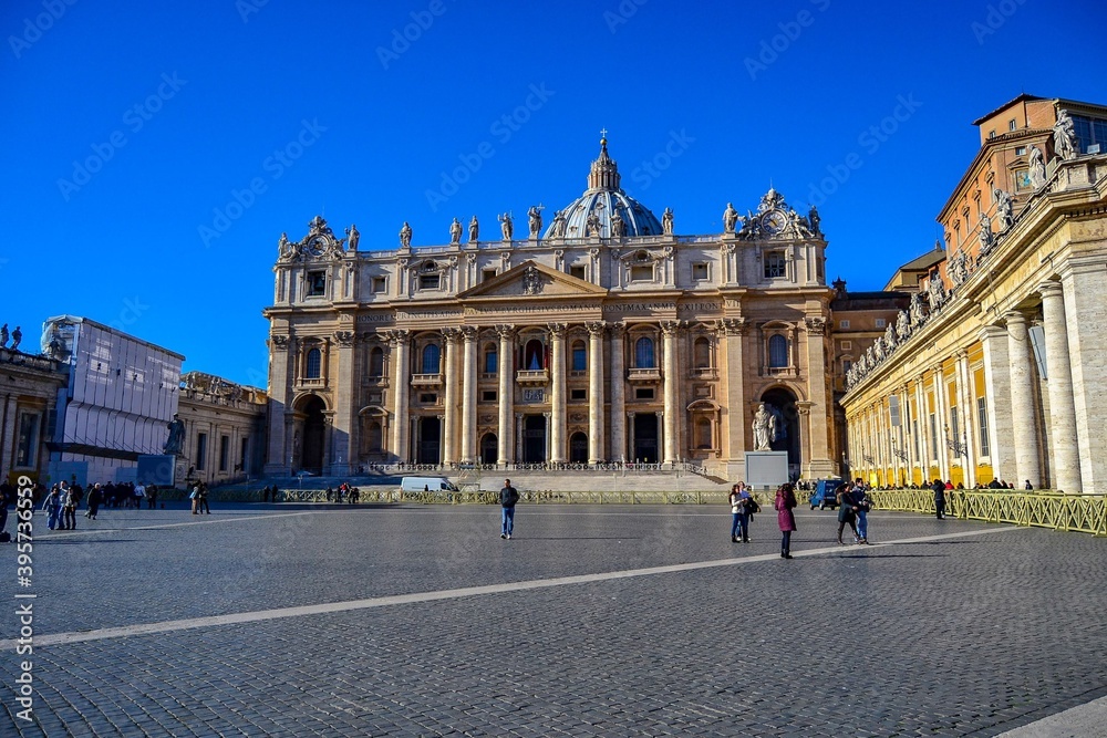 ITALY, VATICAN CITY, 23.12.2011. Main facade and dome of St. Peter's Basilica seen from St. Peter's Square. Tourists walking around the square during sunny day.