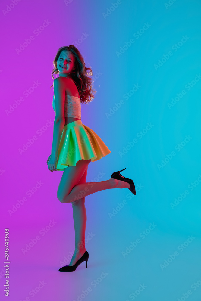 Dancing. Beautiful seductive girl in fashionable yellow skirt on gradient pink-blue neon background. Full-length portrait. Copyspace for ad. Flyer design. Summer, fashion, emotions concept. Dancing. Beautiful seductive girl in fashionable yellow skirt on gradient pink-blue neon background. Full-length portrait. Copyspace for ad. Flyer design. Summer, fashion, emotions concept.