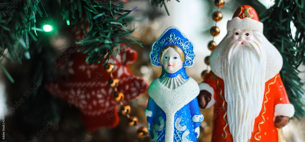 Christmas decorations (Russian Santa Claus and Snow Maiden) standing near with Christmas tree. New Year, holiday background.